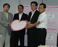 BABY in MEのバッジをハート型の台紙にディスプレイして、賛同企業の方々から三重県産婦人科医会の二井会長に贈呈